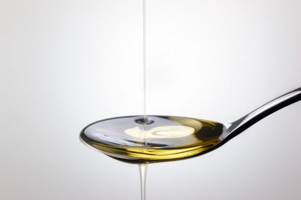 Olive oil pouring into spoon