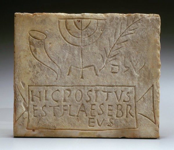 Jewish burial plaque from Italy depicting a shofar, menorah, palm, and text.